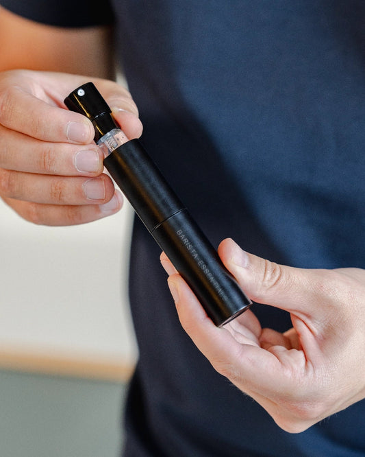 Man trekt glazen spray flesje uit RDT spray houder van Barista-Essentials