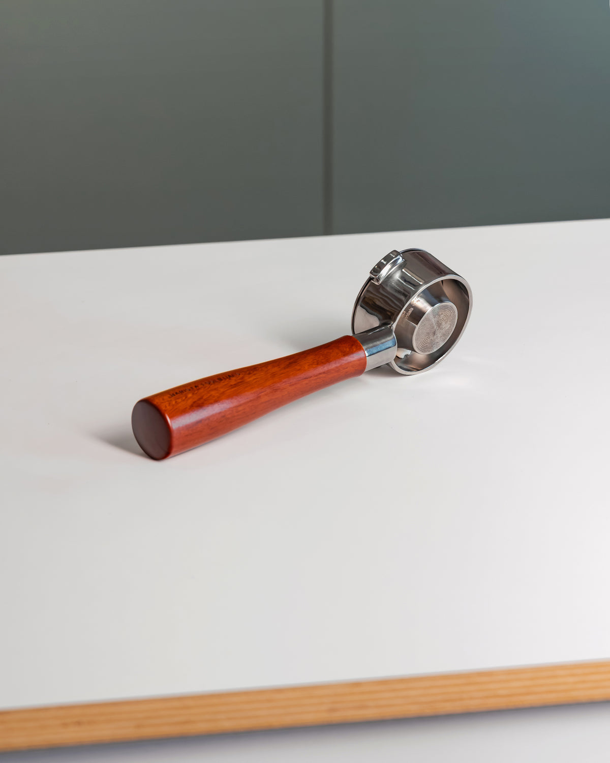 Naked portafilter met houten handvat en convex filterbakje 54mm op tafel