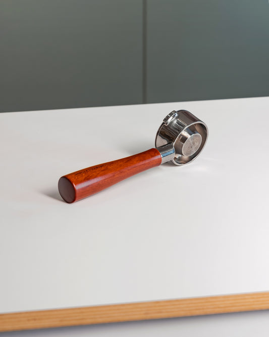 Naked portafilter met houten handvat en convex filterbakje 54mm op tafel