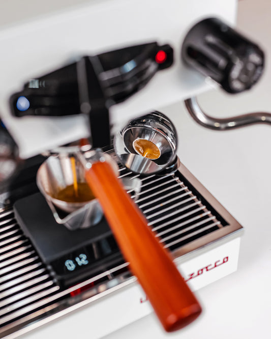 Naked portafilter met convex filterbakje 58mm in een espressomachine, met weegschaal eronder