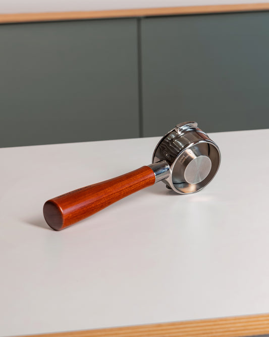 Naked portafilter met houten handvat en convex filterbakje 58mm op tafel