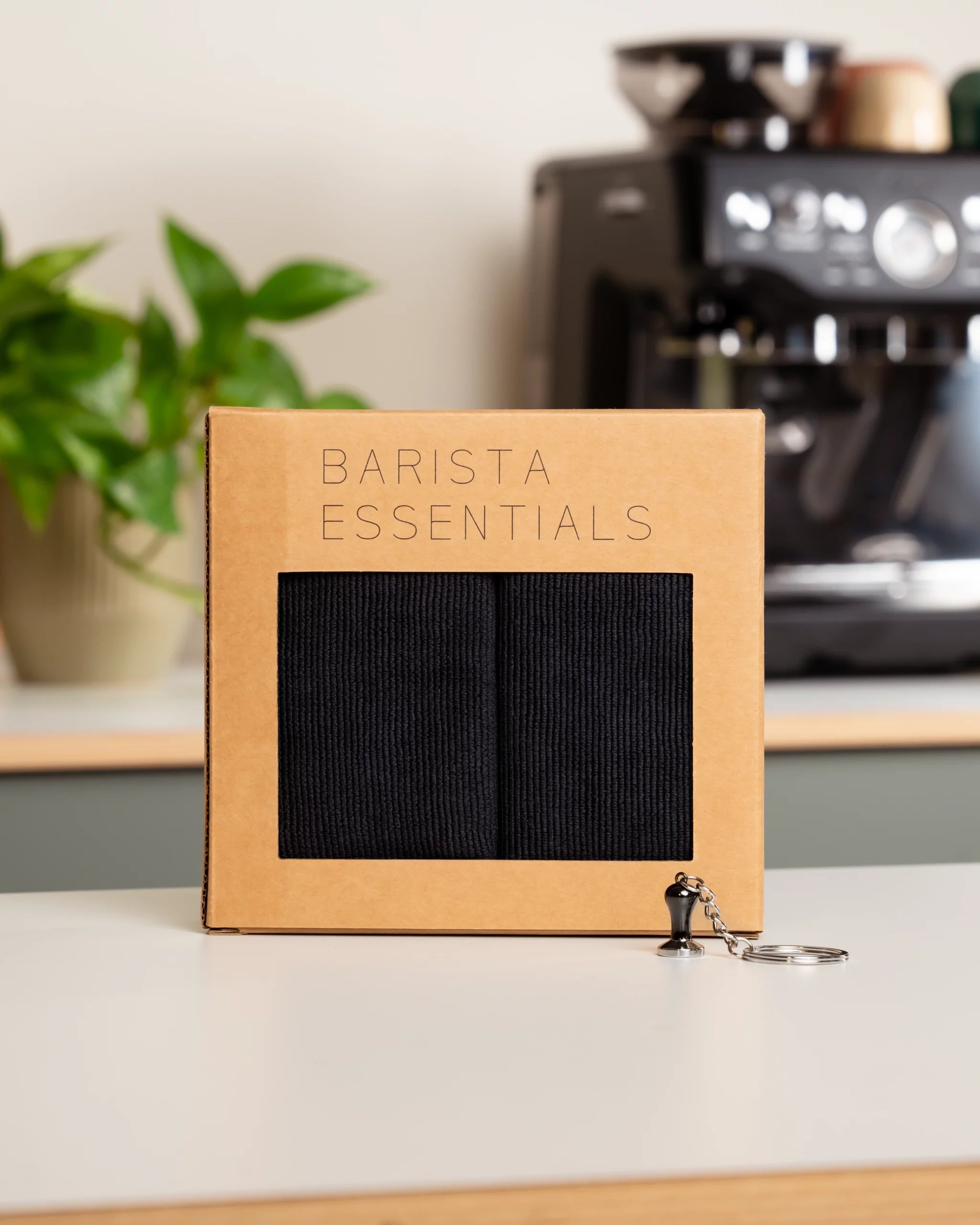 Cadeauset van Barista Essentials voor thuisbarista's met zwarte barista doekjes en een sleutelhanger van een tamper