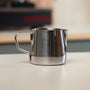 Stainless steel espresso pitcher in a coffee corner