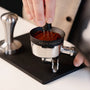 Vlakke tampermat van Barista Essentials waar puck prep wordt gedaan met een portafilter, tamper, WDT-tool en doseerring