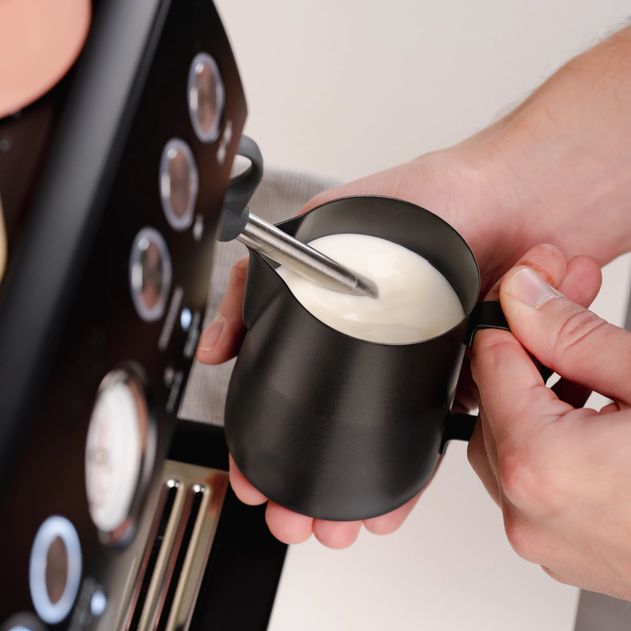 Melkopschuimen in melkkannetje set in het zwart voor latte art voor één en twee cappuccino