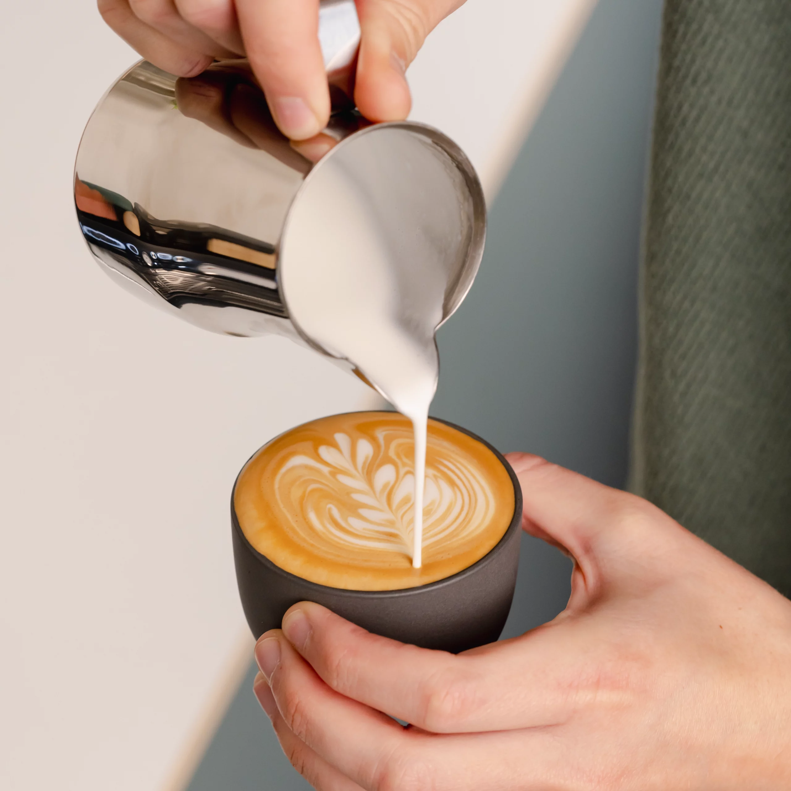 Barista schenkt latte art met melkkannetje set Italiaanse stijl van RVS voor één en twee cappuccino