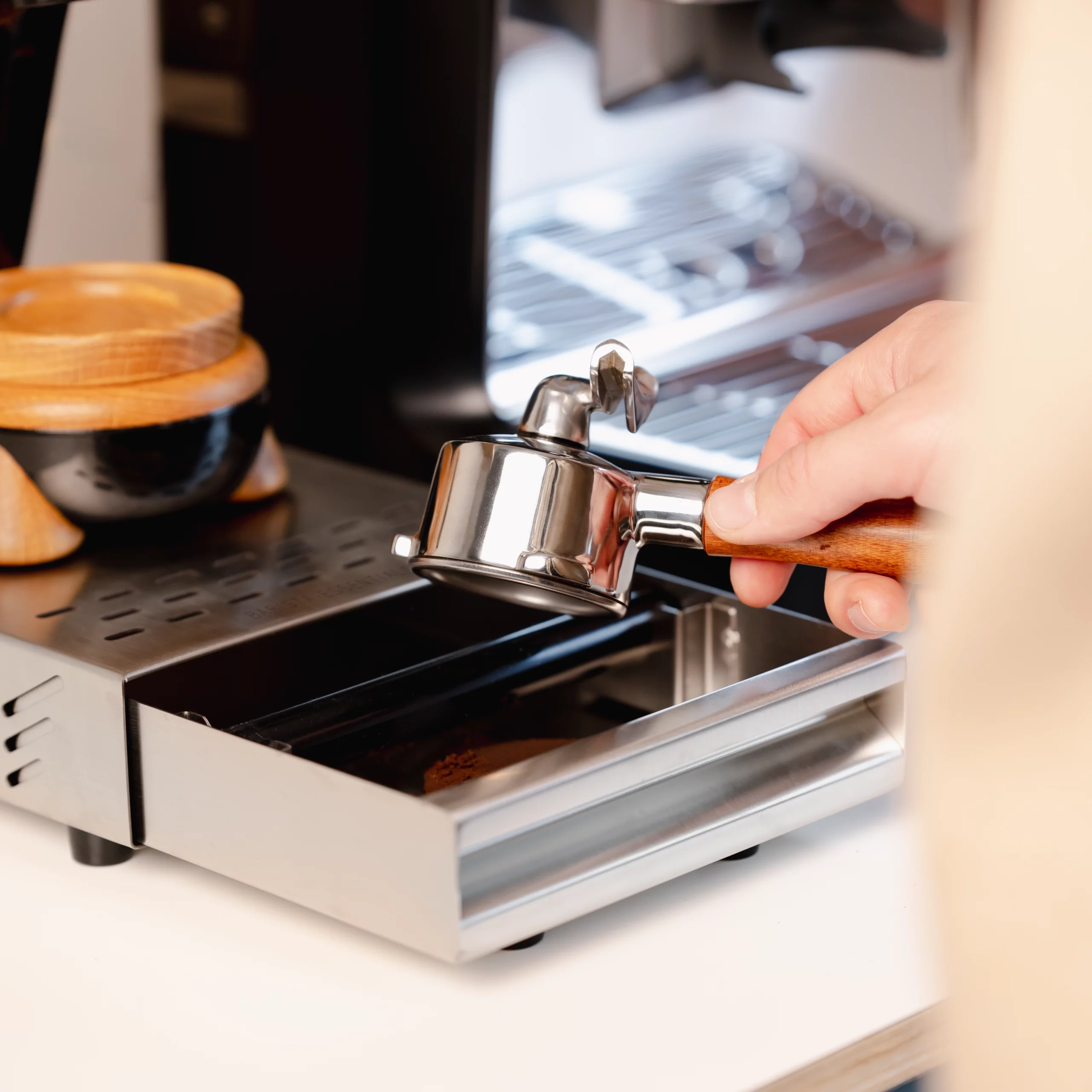 Portafilter uitkloppen in compacte zilverkleurige RVS uitkloplade van Barista-Essentials