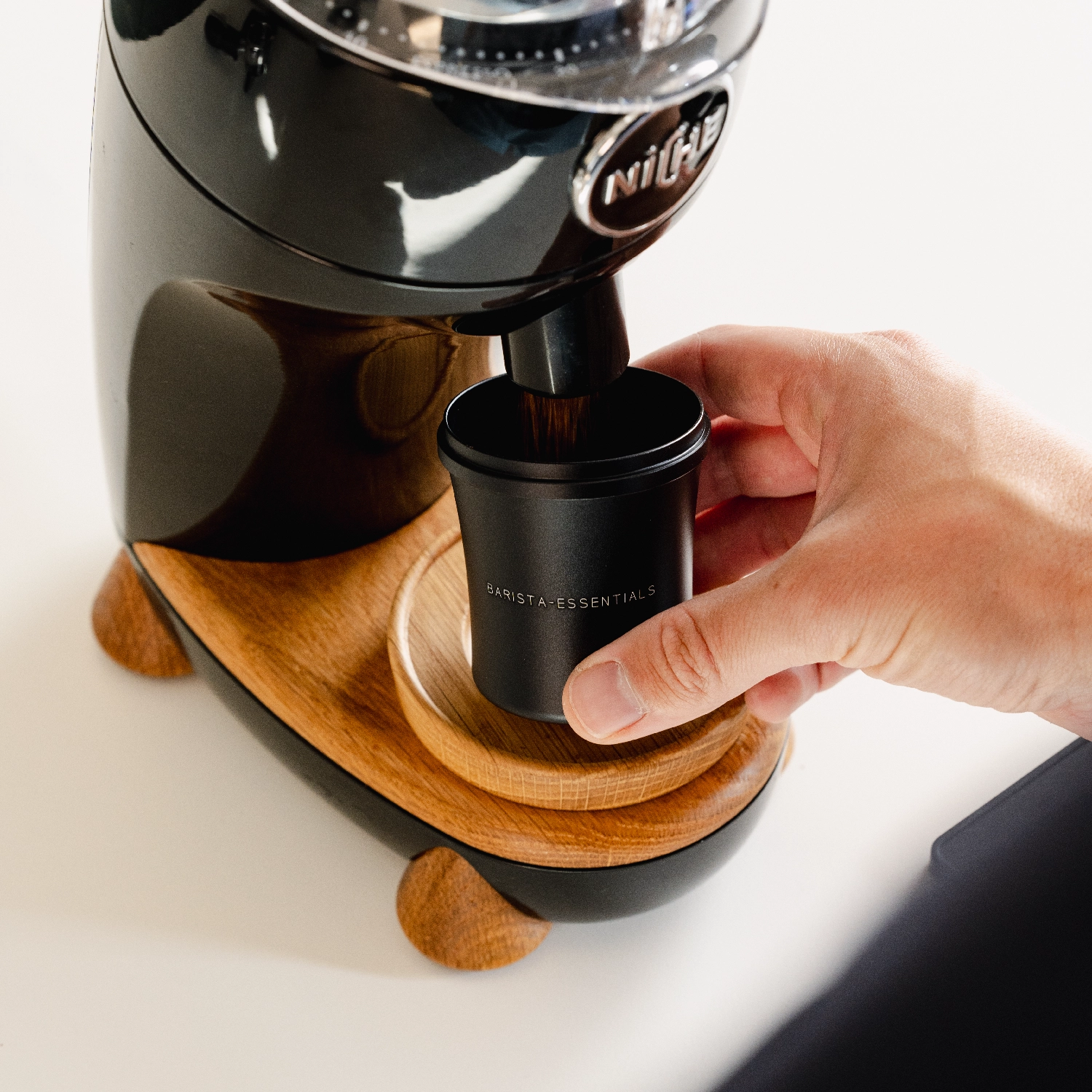 Barista met zwarte 58mm doseerbeker voor E61 of 58mm espresso machines onder niche bonenmaler